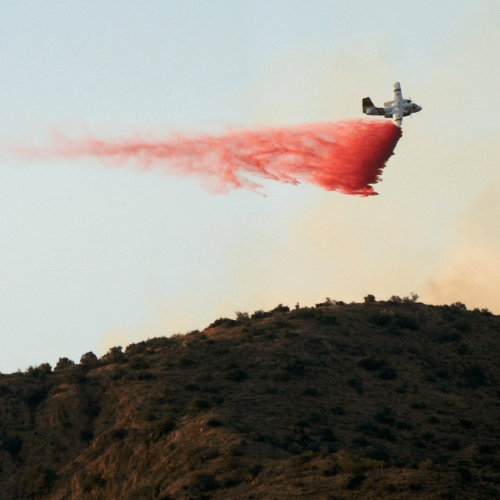 A water bomber sprays an Okanagan hillside to prevent the spread of fire